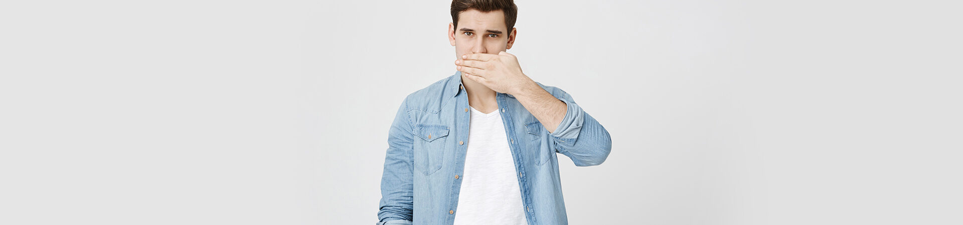 Boy covering his mouth because of bad breath.